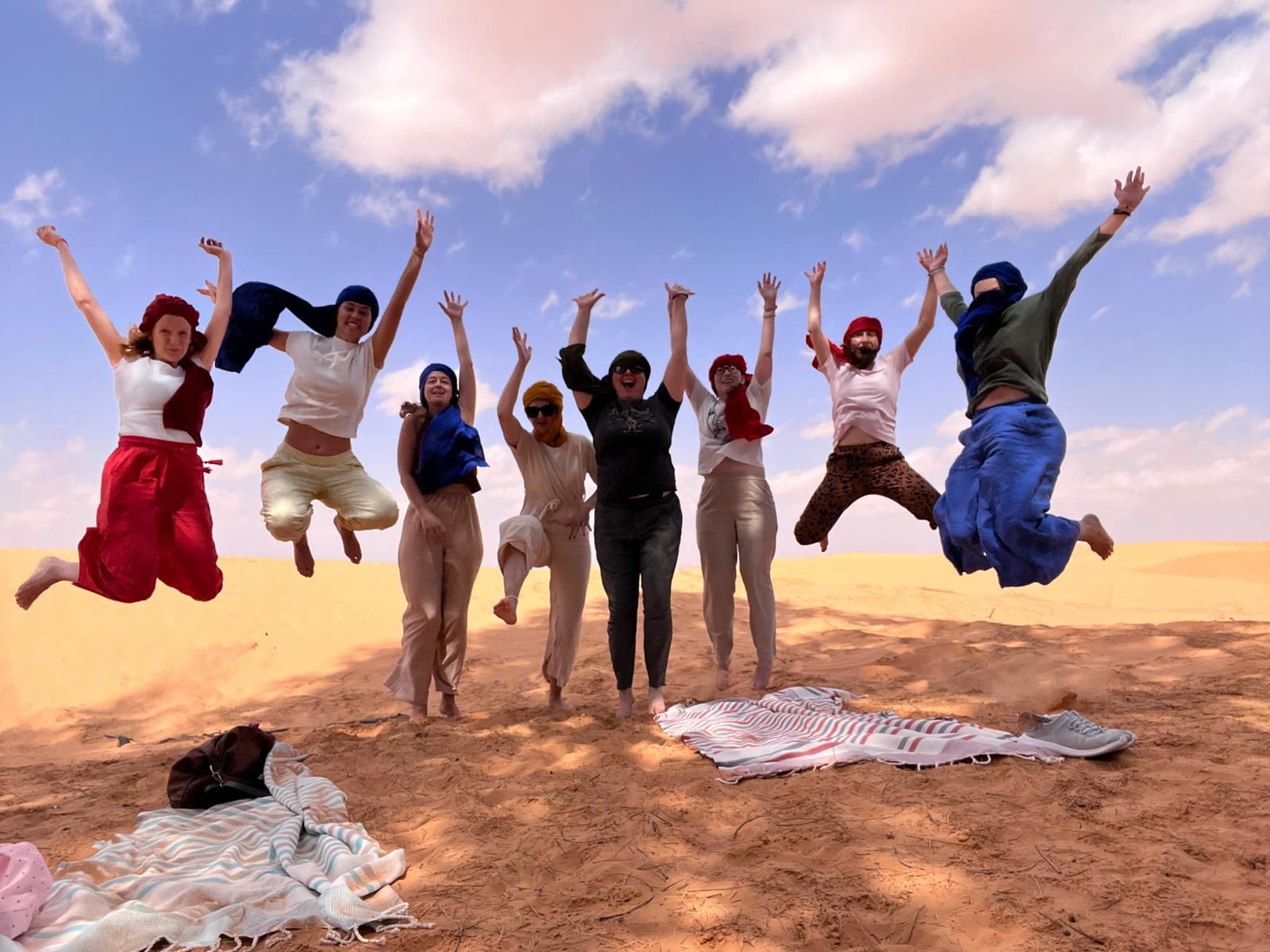 Participants jumping on a sand dune in the desert