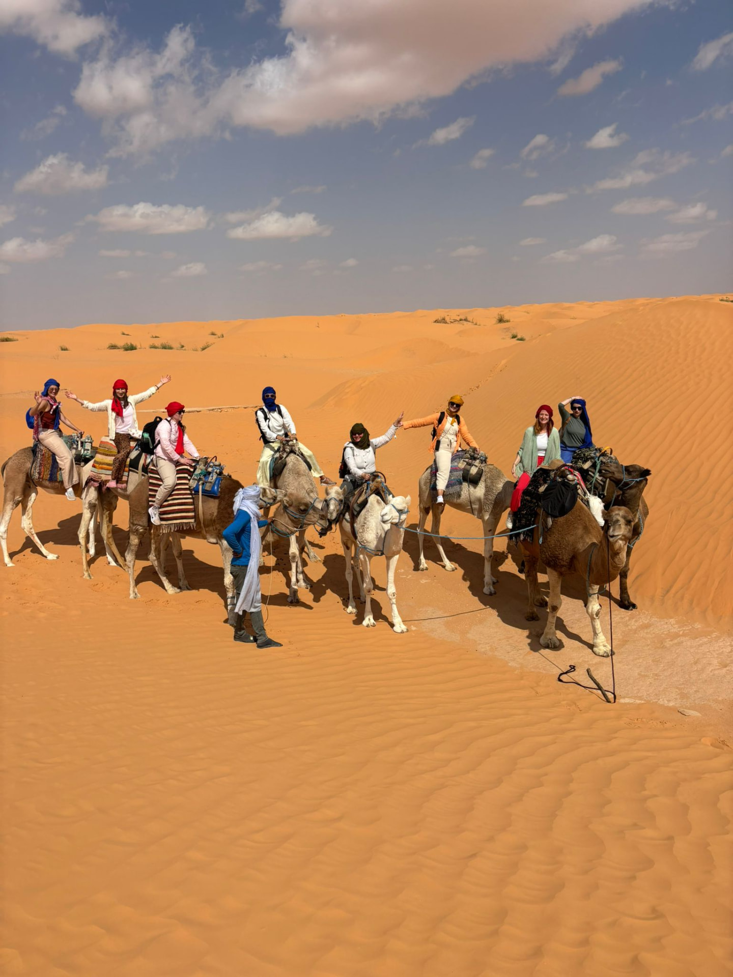 Group riding camels across the dunes in the Tunisian desert