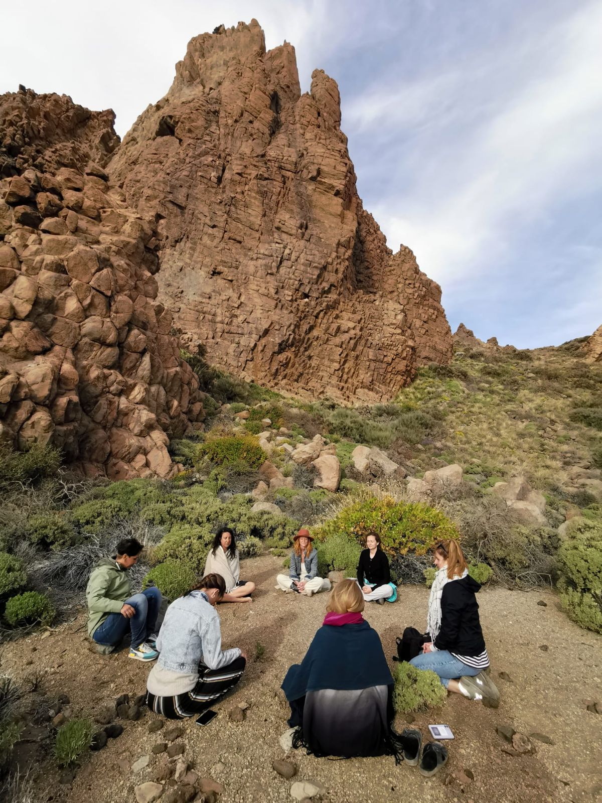 Group sitting in circle beneath the rocky peaks of Teide in Tenerife